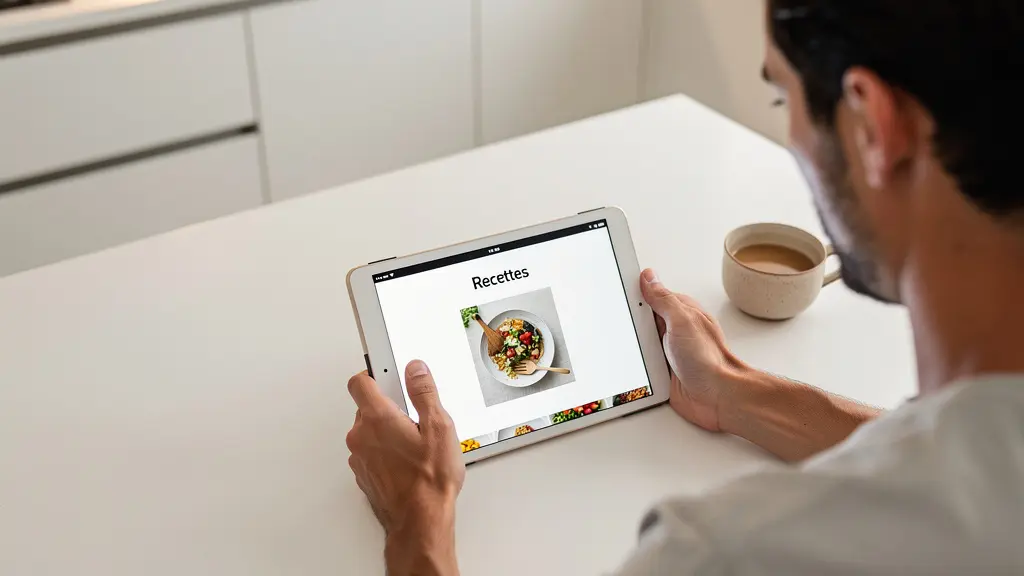 Personne française calculant son budget immobilier sur tablette dans cuisine