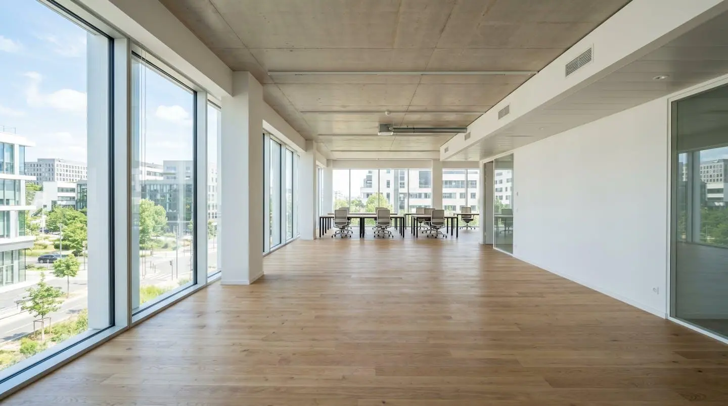 Espace de bureau contemporain vide avec grandes baies vitrées laissant entrer une lumière naturelle abondante, architecture française 2026